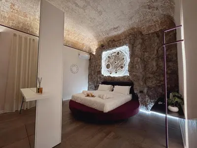 a bedroom with a bed in front of a stone wall at Corona Suite & Rooms in Palermo
