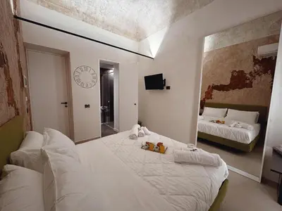 a bedroom with two beds and a clock on the wall at Corona Suite & Rooms in Palermo