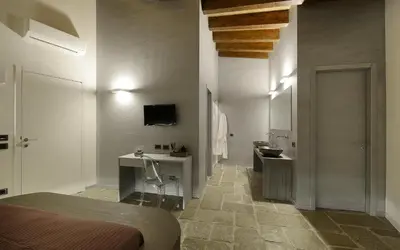 a bedroom with a bed and a bathroom with a sink at Agrirelais Principe SPA in San Giuseppe Jato