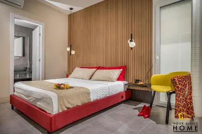 a bedroom with a red bed and a yellow chair at Appartamenti in villa Ionio vista mare con piscina riscaldata e campo da bocce in Alcamo