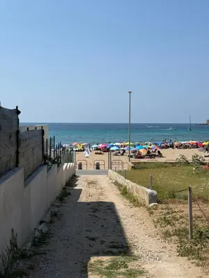 a dirt road leading to a beach with umbrellas at Magaggiari Beach House in Cinisi
