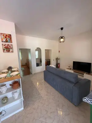 a living room with a blue couch and a television at Magaggiari Beach House in Cinisi