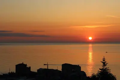a sunset over the ocean with the sun setting at A' Terrazza in Santa Flavia