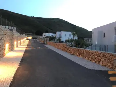 an empty street with a stone wall and buildings at Giardino degli Allori, Villa Manfredi with Pool in Castellammare del Golfo
