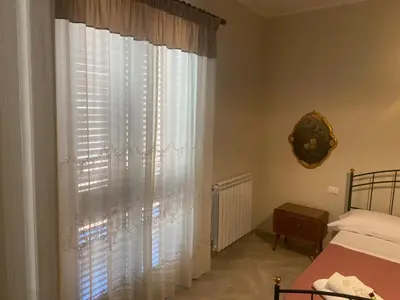 a bedroom with a bed and a window with white curtains at 4 Seasons in Altavilla Milicia