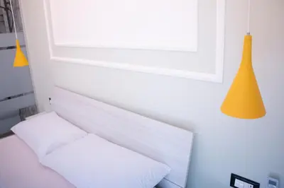 a bed with two white pillows and a yellow lamp at San Carlo Cuore di Palermo in Palermo