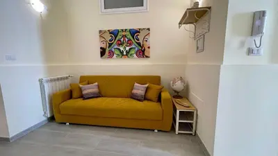 a yellow couch in a room with a painting on the wall at Chez D'Ossuna con Patio Privato - centro storico Cattedrale - ampio 6 ospiti in Palermo