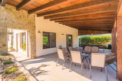 a patio with a table and chairs and a wooden ceiling at Villa Deluxe in Campofelice di Roccella