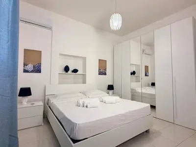 a white bedroom with a bed and a mirror at Villa GioEle - Pool & Relax in Mandra Capreria