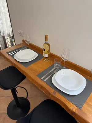 a wooden table with two white plates and a bottle of wine at Domus Vucciria in Palermo