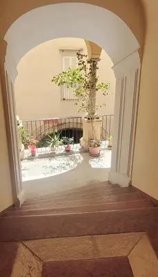 an archway leading into a courtyard with potted plants at Maison S Elena in Palermo