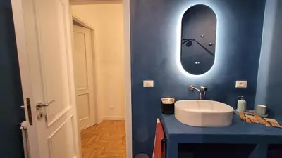 a bathroom with a sink and a mirror on a blue wall at Maison S Elena in Palermo