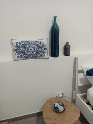a table with a bottle and a vase on a shelf at Naima House in Palermo