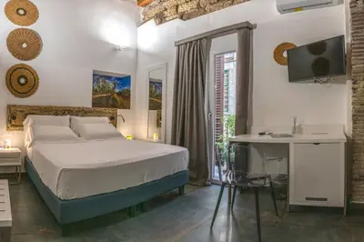a bedroom with a bed and a desk with a computer at Ballarooms Experience in Palermo