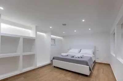 a white bedroom with a bed and white shelves at Luxury Royal House in Palermo