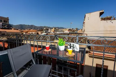 a table on a balcony with two cups and a plant at Palermo Centro Le Cupole della Felicissima in Palermo