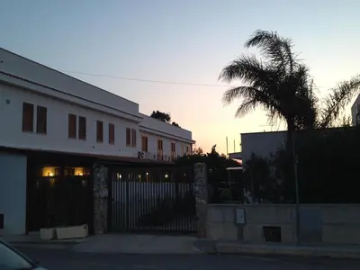 a building with a gate and a palm tree at Hotel Il Pirata in Cinisi