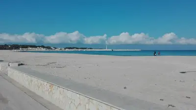a beach with people walking on the sand and the water at Aquilone in Castelluzzo
