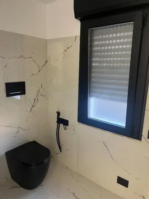 a bathroom with a black toilet and a window at Suit home Archimede in Palermo