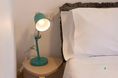 a green lamp on a table next to a bed at ESSE Homes Sant Elia in Santa Flavia