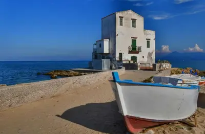 a boat sitting on the beach next to a building at ESSE Homes Sant Elia in Santa Flavia