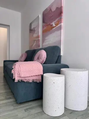 a blue couch with a pink blanket and two white stools at Cocciu d'amuri a casa in Terrasini
