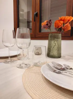 a table with three wine glasses and a vase with flowers at Appartamento Dante 2 in Alcamo