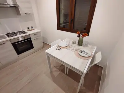 a white table and chairs in a kitchen with a stove at Appartamento Dante 2 in Alcamo