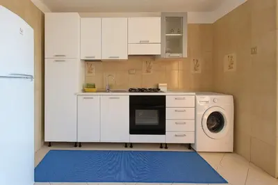 a kitchen with white cabinets and a washing machine at Stella Del Mare in Castellammare del Golfo