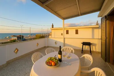 a table with a bowl of fruit on a balcony at Stella Del Mare in Castellammare del Golfo
