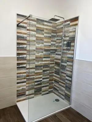 a shower with a glass door and wood panels at kalispera in Cinisi