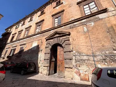 an old brick building with a door and cars parked outside at Ciak a Ballarò in Palermo