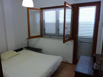 a bedroom with a bed and two windows and a table at Terrazza 3F Mondello in Palermo