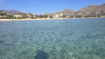 a large body of water with a beach and mountains at Almarè Mondello in Mondello
