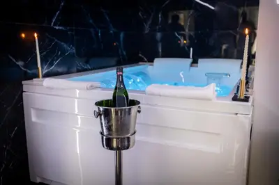 a bottle of wine in a bucket next to a tub at Palermo Luxury Rooms Black in Palermo