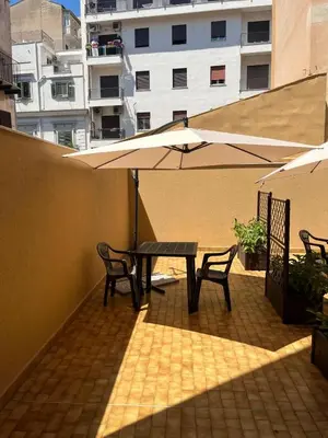 a patio with a table and chairs and an umbrella at Le Stanze del Massimo in Palermo