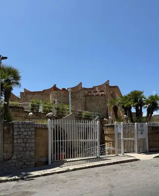 a white fence in front of a building with palm trees at Mondello Sunshine Apartment in Mondello