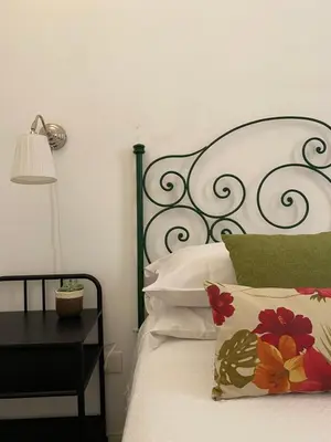 a bed with a black headboard and a table with a lamp at Alvorada Rooms in Palermo