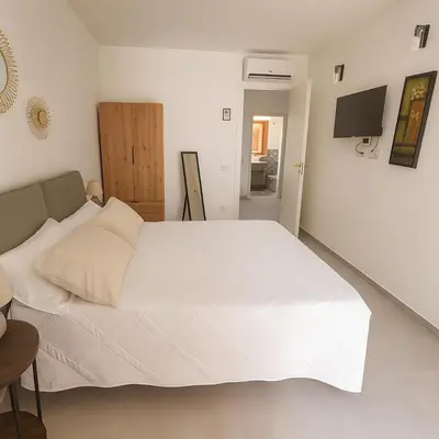 a bedroom with a white bed and a television at Borgo di Mare in Palermo