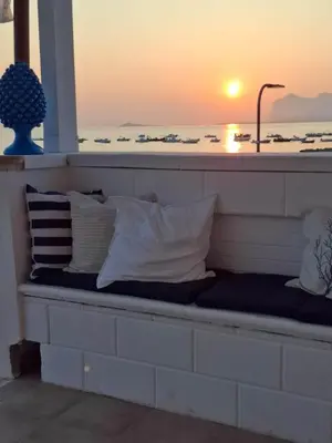 a bench with pillows on it with the sunset at Le Terrazze sul mare Joelle -The uniqueness of the Terrace overlooking the sea in Carini