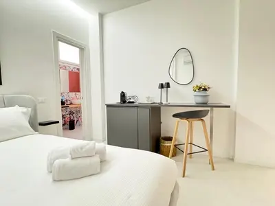 a white bedroom with a bed and a mirror at Mama suites Politeama in Palermo