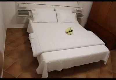 a white bed with a flower on top of it at Homedaf in Carini