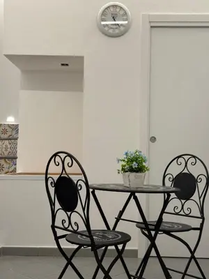 two chairs and a table in a kitchen with a clock at VUCCIRIA' S ROOM centro storico in Palermo