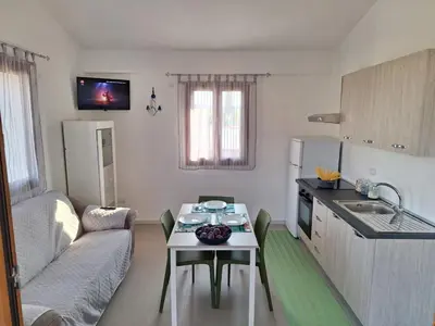 a kitchen and a living room with a table and a couch at La Marina Pool Villa in Trappeto