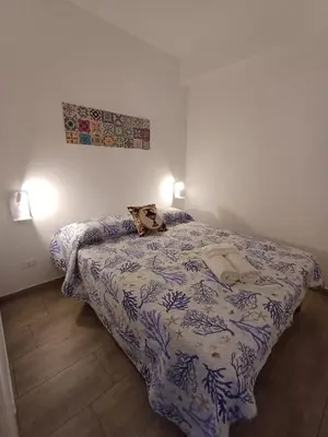 a bedroom with a bed with a blue and white comforter at Studio 23 in Partinico