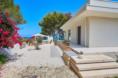 a house with stairs next to a yard with flowers at Villa Marinjo in Alcamo