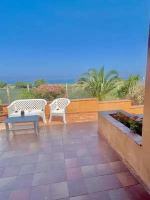 two chairs and a table on a patio with the ocean at Villa Fiory in Terrasini