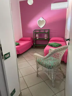 a pink room with two beds and a chair at Villa Fiory in Terrasini