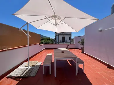 a patio with a table and a white umbrella at Casa TreMar - Flat with roof top in Mondello in Palermo