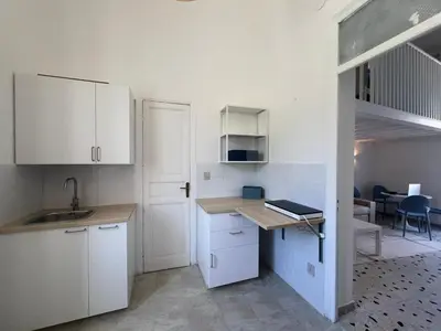 a kitchen with white cabinets and a sink and a table at Casa TreMar - Flat with roof top in Mondello in Palermo